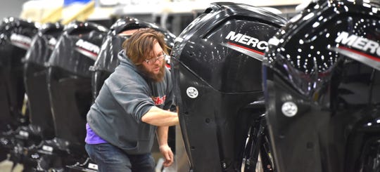 Anderson's Boat Sales employee Blake White waxes Mercury outboards on pontoon boats.