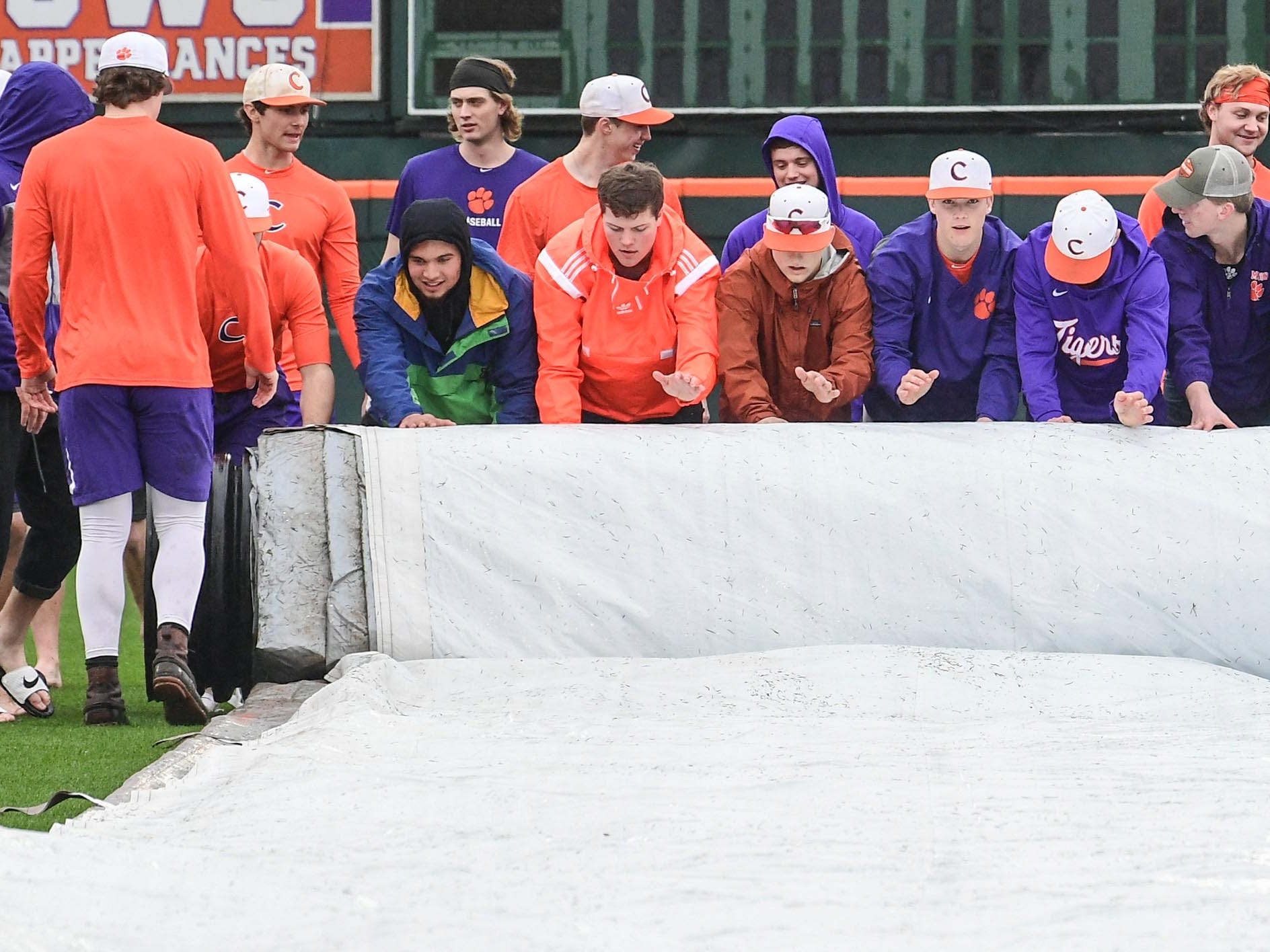 Clemson players help roll up the rain tarp before their first official team Spring practice at Doug Kingsmore Stadium in Clemson Friday, January 24, 2020.