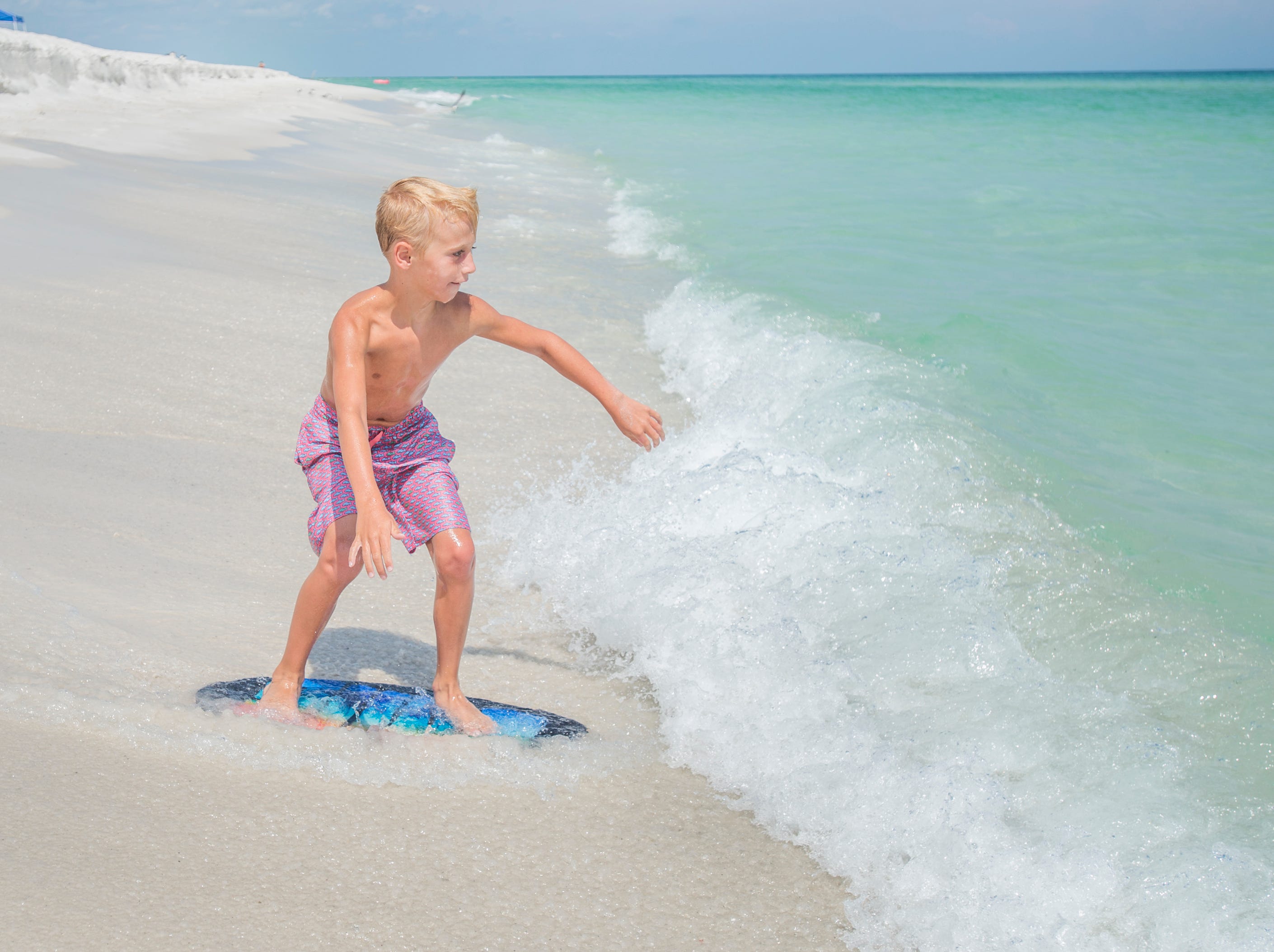 Knox Stephens, 8, of Magnolia, Arkansas, skimboards along Penacola Beach on Friday, July 20, 2018.