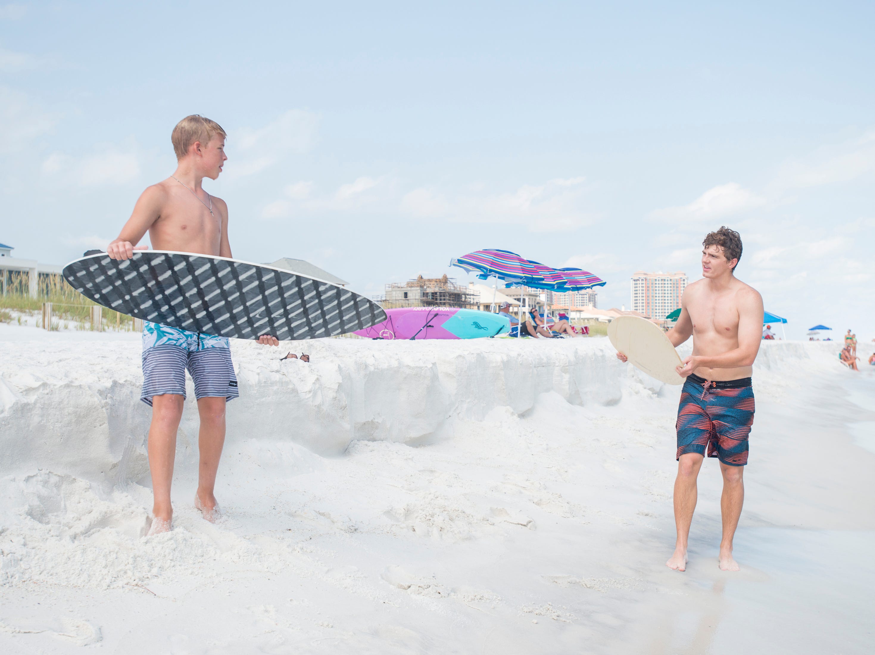 Wyatt West, 14, of New Braunfels, Texas, left, gives Pensacola News Journal sports reporter Eric Wallace a few pointers as he gives skimboarding a try along Penacola Beach on Friday, July 20, 2018.