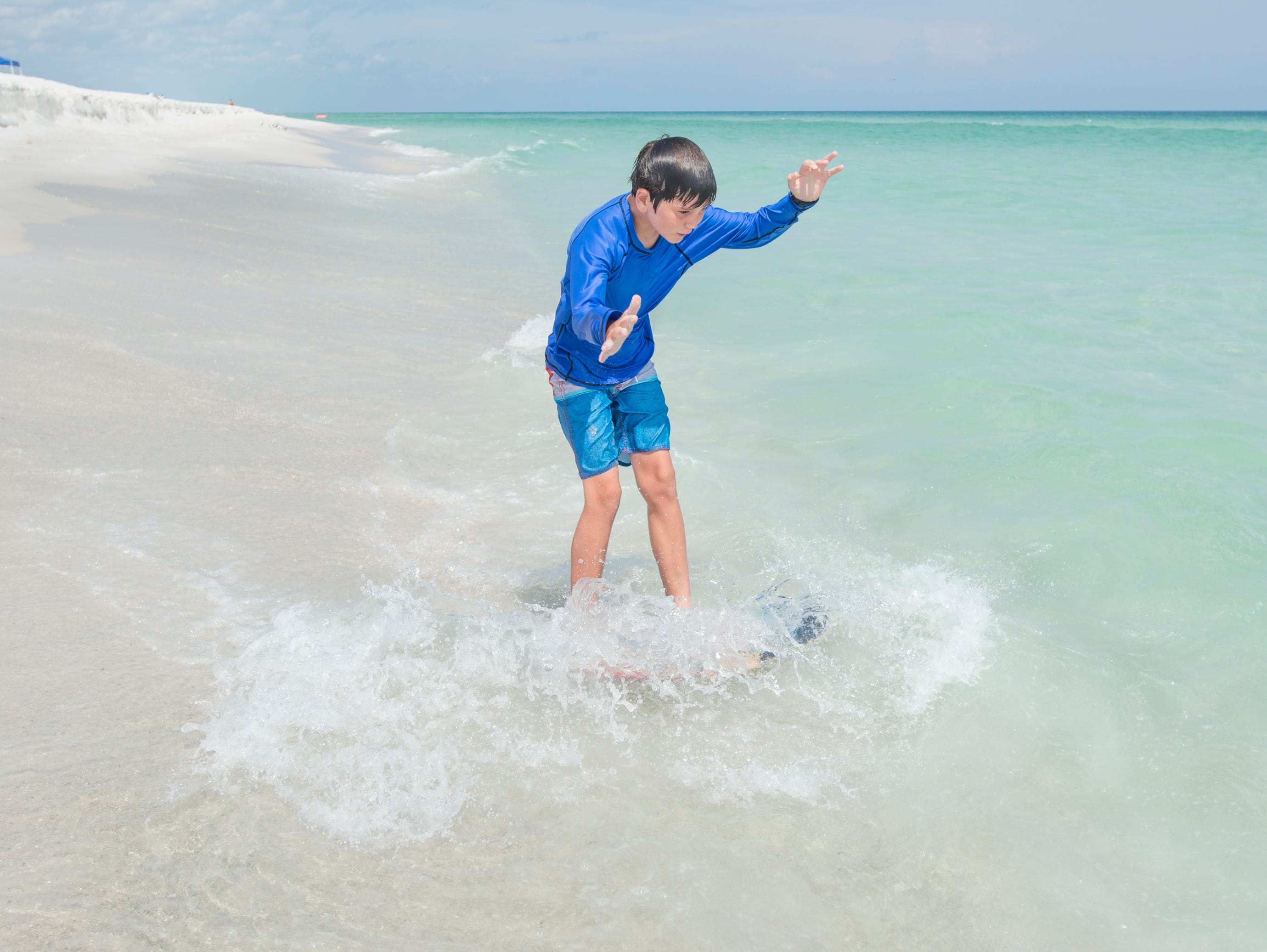 Griffin Wiggins, 9, of Magnolia, Arkansas, skimboards along Penacola Beach on Friday, July 20, 2018.