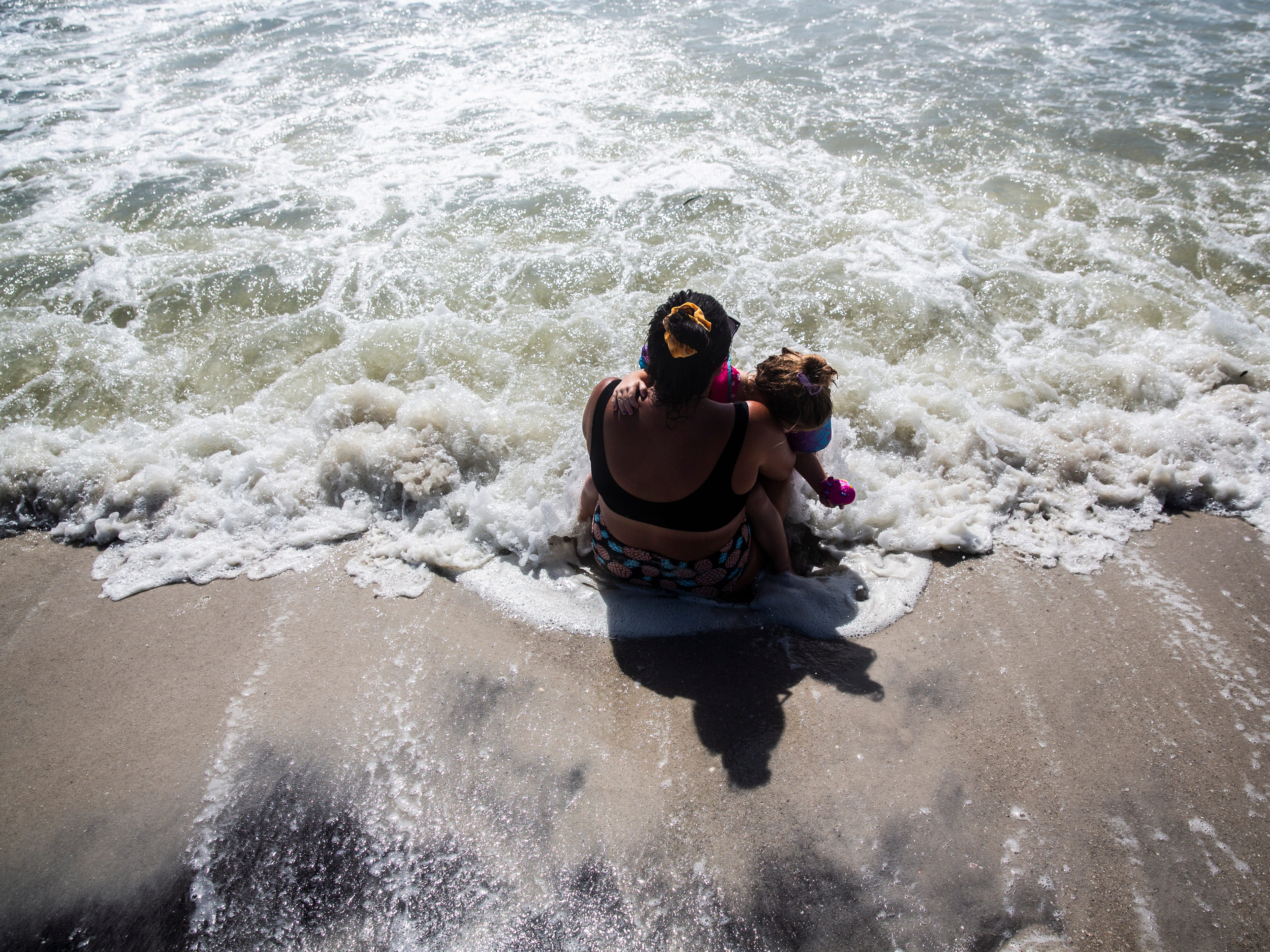 Brittant Cyr holds Brielle Jonathan, 3, in her arms as she sits at the shore of Naples Beach on Tuesday, September 3, 2019. Locals and tourists continue visiting scenic spots in Naples, taking advantage of heavy winds and waves bought on by Hurricane Dorian.