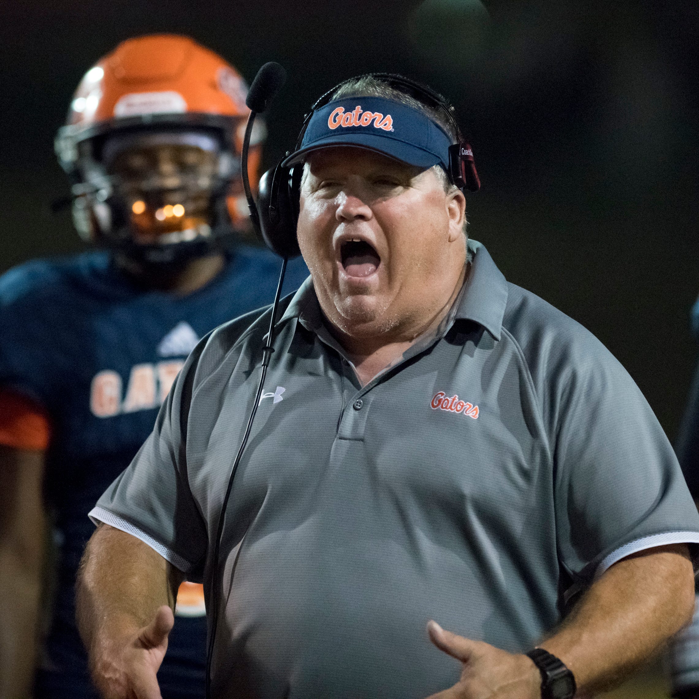 Head coach Mike Bennett communicates with his team during the Booker T. Washington vs. Escambia football game at Escambia High School in Pensacola on Friday, Oct. 25, 2019.