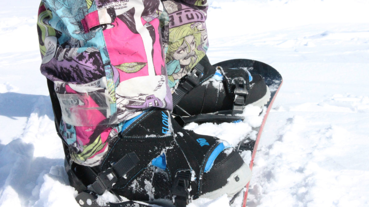 A close up picture of Campbell's pants as he stands on his snowboard