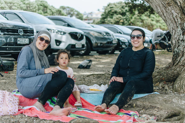 Aliya Alhaddad, Lara Khayyat and Tima Alhaddad eating fish and chips on Milford Beach.