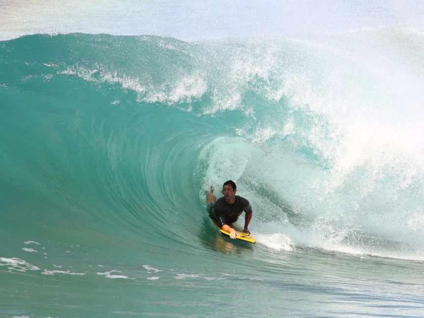 A bodyboarder rides a thick tube.
