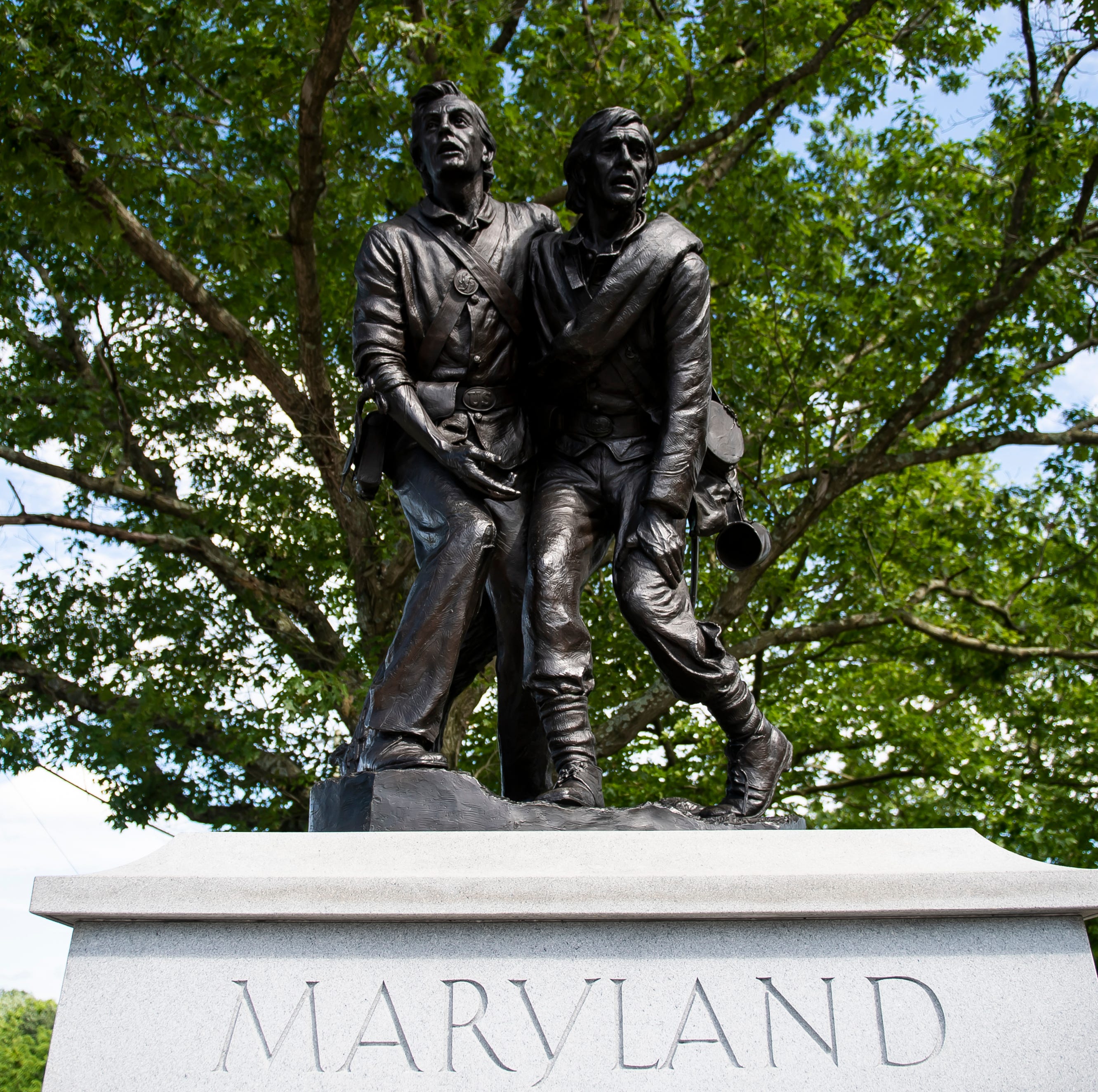 18. State of Maryland monument was dedicated in 1994 and depicts two wounded Marylanders, one Union and one Confederate, helping each other on the battlefield. A list the Maryland commands of both armies that fought at Gettysburg is presented on a tablet on the back of the monument. Location: Along Cyclorama Drive directly off of Taneytown Road. 39.816397, -77.232416