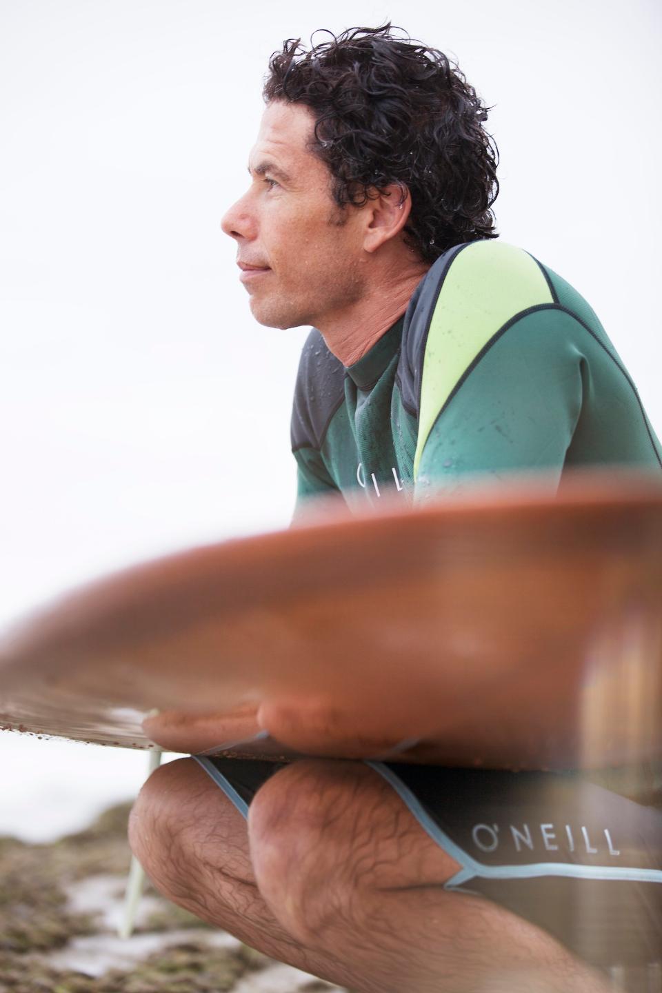 Yogi, sitting next to his surfboard, contemplates the ocean.