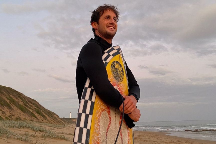 Surfer Joe Draffen with his board on the beach at Fairhaven, Victoria.