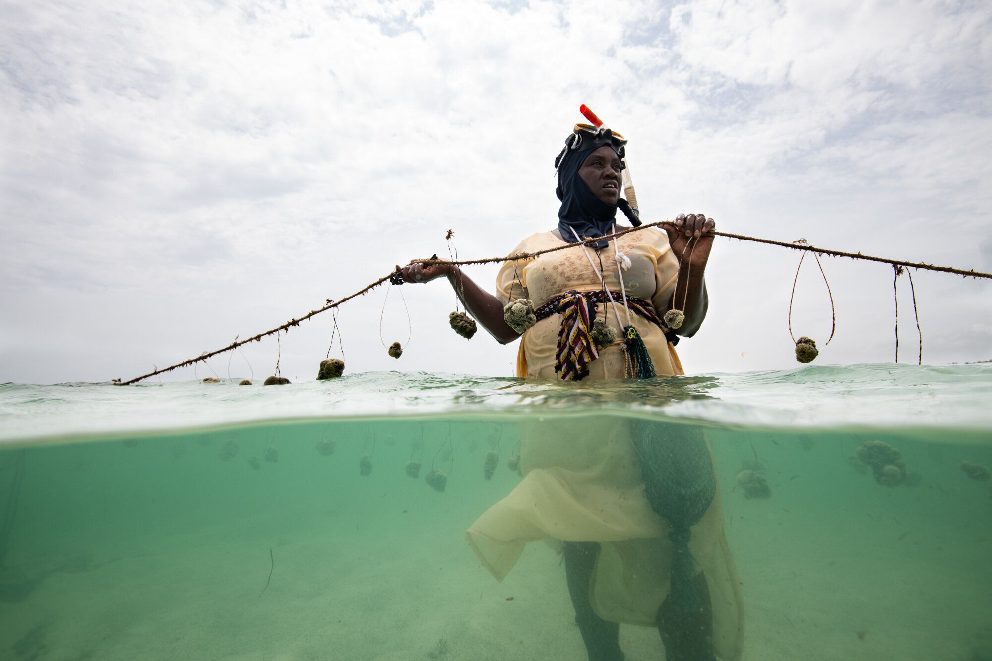 Nasir Hassan Haji holds a rope of sponges on her farm. She was one of the first 2 sponge farmers in Jambiani and previously f