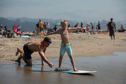 Ken Morshead propels Levi Morshead into the water on a skim board at Capitola Beach (Santa Cruz County) on Friday.