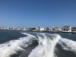 a man riding a wave on top of a body of water: Reporter Carly Mallenbaum tries out wakeboarding for the first time this summer.