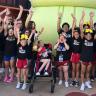 a group of people standing in front of a crowd posing for the camera: Mom creates cheer team for kids with special needs