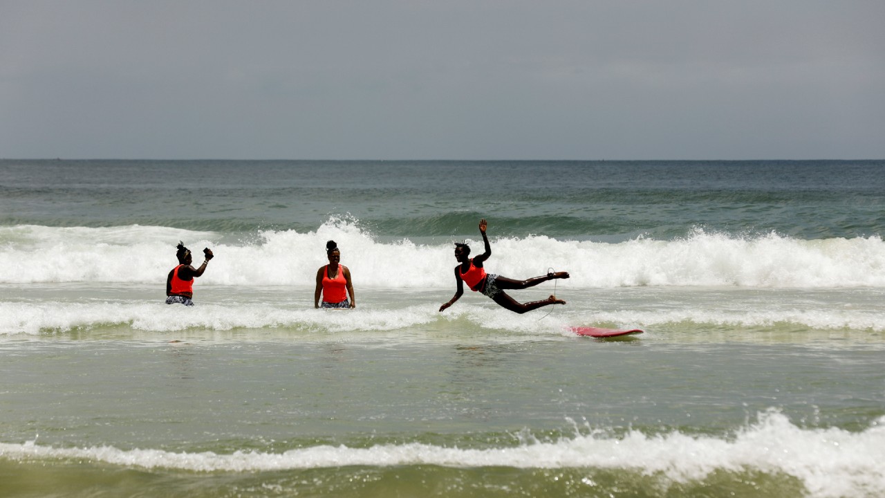 Sambe, Senegal's first female professional surfer, and Rhonda Harper, the founder of BGS, a training school for girls and women who want to compete in professional surfing, teach a young surfer during a training session at Yoff district, Dakar. Sambe went to California in 2018 to train with BGS. (Image: Reuters)