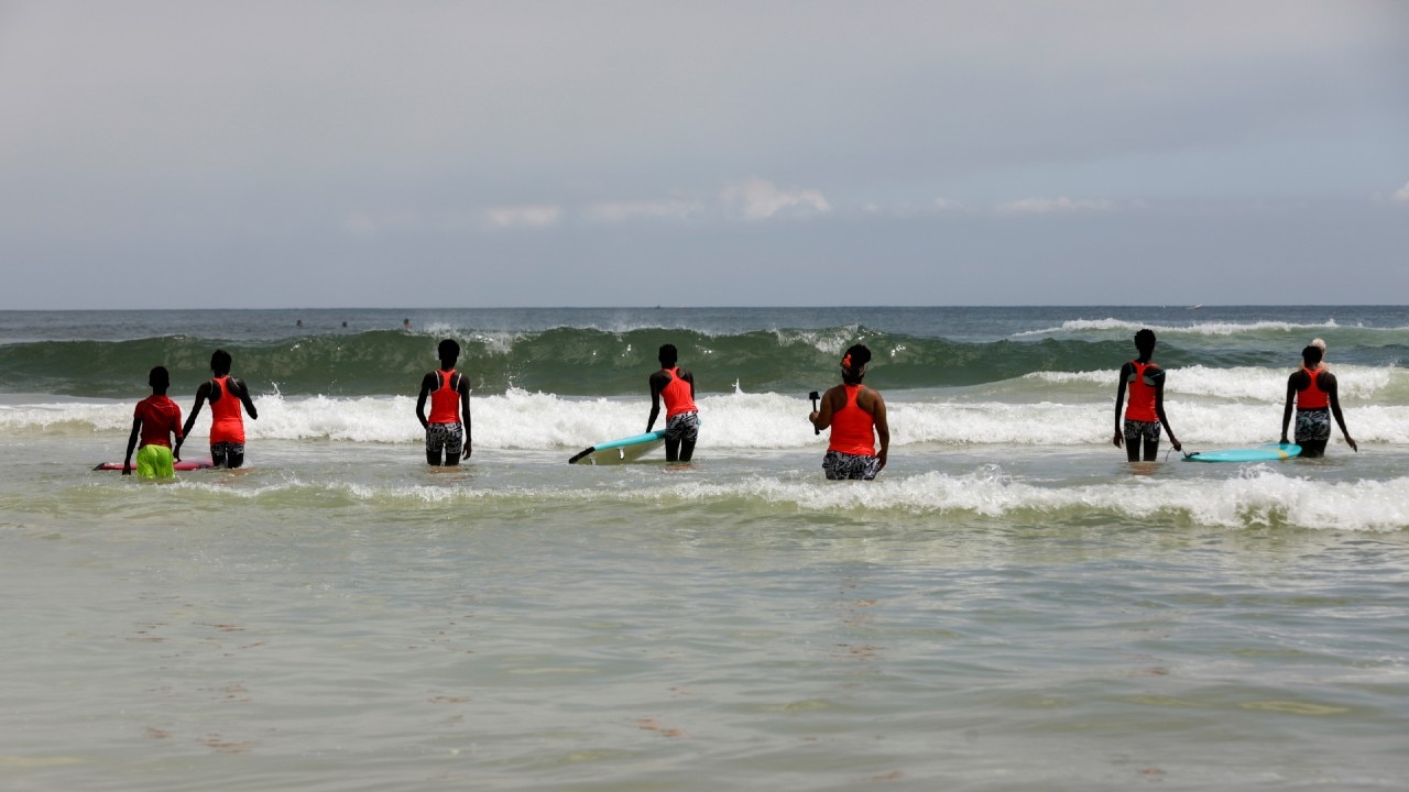 Beginners learning how to surf, enter the sea during a training session coached by Sambe and Harper at Yoff district, Dakar. (Image: Reuters)