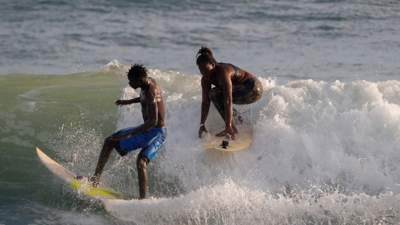 Sambe surfs with her friend Madicke Mbengue during a training session in Ngor, Dakar. (Image: Reuters)