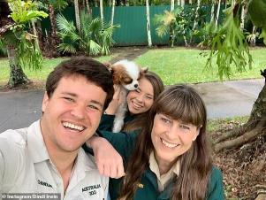 Terri Irwin et al. posing for the camera: Glowing and gorgeous: She recently shared her baby's first sonogram with fans. And on Wednesday, pregnant Bindi Irwin was simply glowing in a selfie with her husband Chandler Powell and her mother Terri