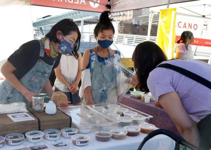 Mariko Grady (left) and Kana Weaver (center) helps a customer at the Aedan Fermented Foods stand at the Ferry Plaza Farmers Market in San Francisco, Calif. on Saturday, Sept. 26, 2020.